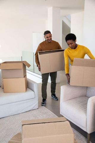 Couple in modern living room carrying moving boxes during relocation