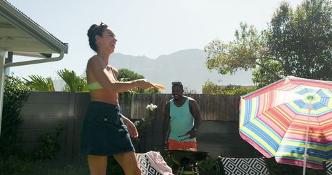 Friends Enjoying Outdoor Frisbee Game with Barbecue