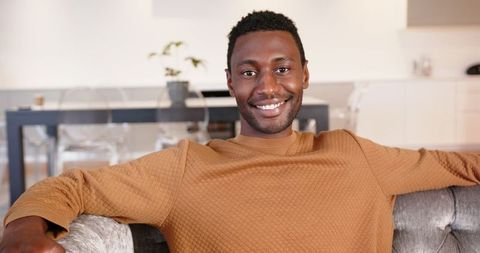 Joyful Man Relaxing on Sofa in Modern Apartment with Coffee