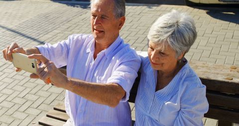 Senior couple taking selfie outdoors in sunlight