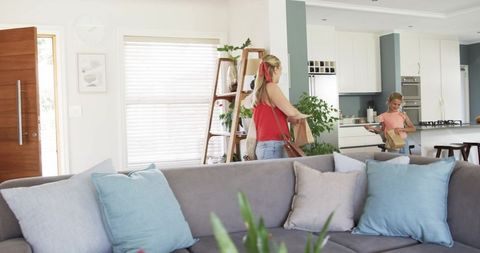 Mother carrying groceries with daughter in bright modern open-plan living room and kitchen