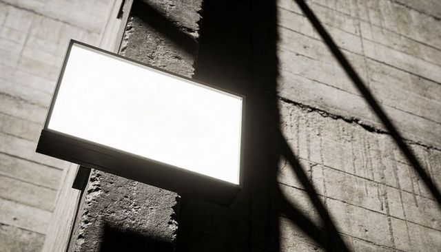 Glowing rectangular light panel mounted on concrete wall casting strong diagonal shadows