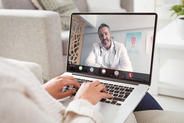 This image depicts a woman having a video consultation with a doctor from the comfort of her home. It can be used for healthcare websites, articles on telemedicine, patient information pamphlets about remote consultation options, or technology’s role in modern healthcare.