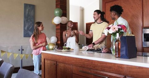 Diverse group toasting in modern kitchen with festive balloons