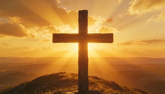 Wooden christian cross silhouetting on hilltop at sunrise, radiant sunbeams and golden sky