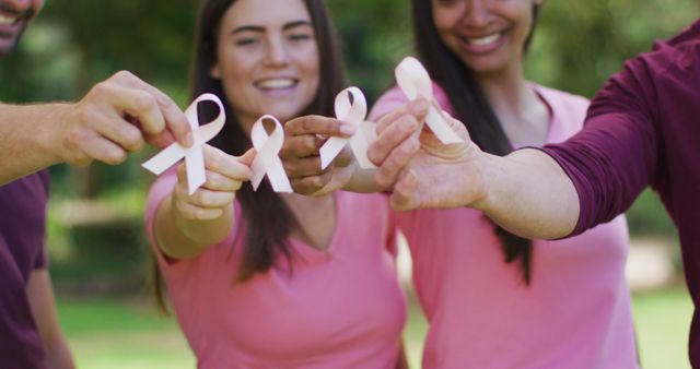 Portrait of diverse group of men and women smiling and holding breast cancer ribbons in park - Download Free Stock Photos Pikwizard.com
