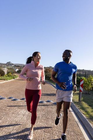 Couple jogging along suburban path on clear day in sport attire
