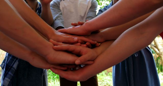 A diverse group of individuals places their hands together in a gesture of unity and teamwork, with copy space. This symbolizes collaboration and support among people from various backgrounds.