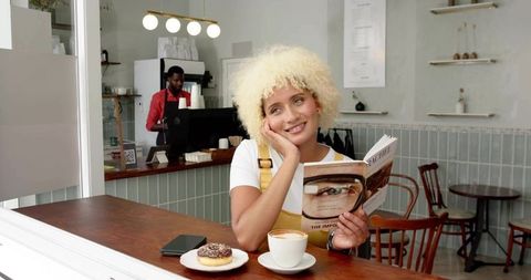 Woman Enjoying Coffee and Reading in Cozy Café
