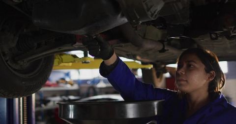 Mechanic Tightening Bolt Under Vehicle in Auto Repair Shop