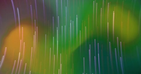 Vertical glowing light trails cascading through green and amber bokeh abstract gradient