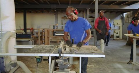 Skilled Craftsmen Using Table Saw in Bustling Workshop