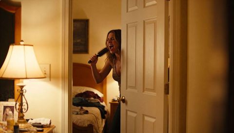 Singing woman leaning in bedroom doorway with hairbrush, cozy late-night solo performance