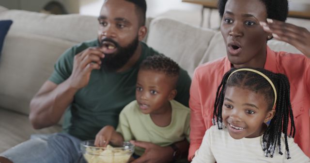 Happy african american family eating popcorn and supporting on couch at home - Download Free Stock Photos Pikwizard.com