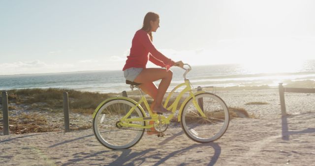 Happy caucasian woman riding a bike on the beach by the sea. beach stop off on summer holiday road trip.