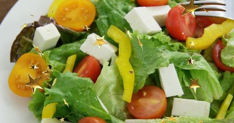 Fresh salad flatlay with feta, cherry tomatoes, yellow pepper and gold star overlay