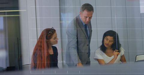 Pointing executive guiding team during analytics review in modern glass boardroom