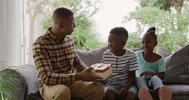 Father Giving Gift to Happy Children on Sofa at Home - Download Free Stock Images Pikwizard.com