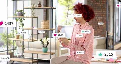 Social creator checking phone in sunlit loft office with engagement notifications