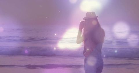 Dreamy beach sunset with woman reflected in lens flare