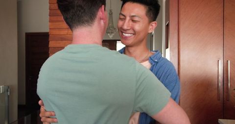 Joyful Same-Sex Couple Dancing Among Moving Boxes at New Home