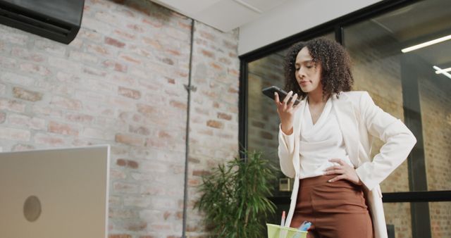 Confident Businesswoman Voicing Notes Through Mobile Device in Modern Office - Download Free Stock Images Pikwizard.com