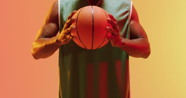 Image of african american male basketball player holding ball on orange background. Sports and competition concept.