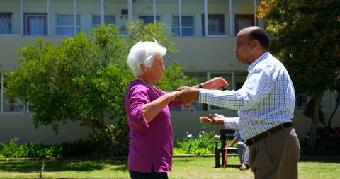 Interracial Elderly Couple Dancing in Garden