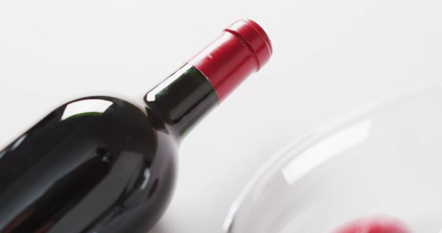 Featuring a red wine bottle with a red wax seal alongside a wineglass on a minimalist background. Ideal for use in wine advertisements, beverage promotions, restaurant menus, or social media posts targeting wine enthusiasts. Suitable for conveying a sense of elegance, luxury, and celebration.