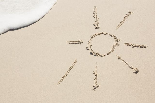 Sun drawn on sand at beach