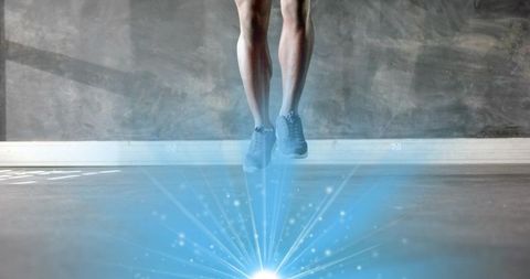Male athlete jumping and hovering above studio floor with cyan light beams
