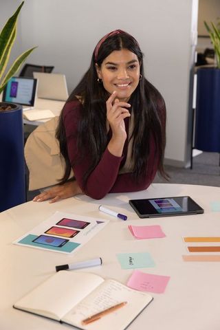 Creative designer leaning over table reviewing mobile app mockups in office workspace