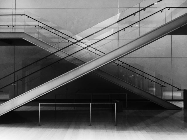 This image captures a minimalist modern staircase in a contemporary building. With its sleek lines, geometric design, and black-and-white color scheme, it represents modern architecture and urban interior design. Ideal for use in articles about architecture, minimalism, interior design, or urban development.