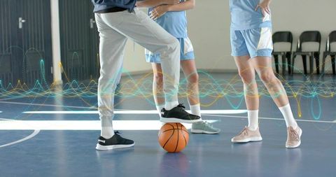 Teen athletes balancing on basketball during gym drill with digital waveform overlay
