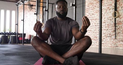 African American Man Meditating in gym on Pink Yoga Mat