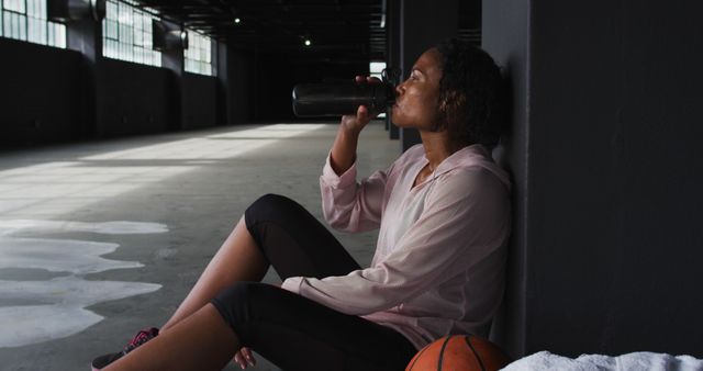 Female Athlete Taking Break and Hydrating during Indoor Basketball Practice - Download Free Stock Images Pikwizard.com