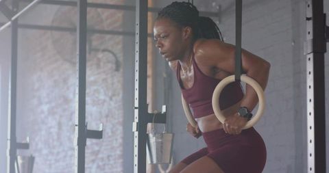 Woman Performing Ring Dips on Wooden Rings in Industrial Gym Calisthenics Strength Training
