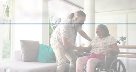 Caregiver helping woman in wheelchair at home holding pink bouquet, offering gentle support