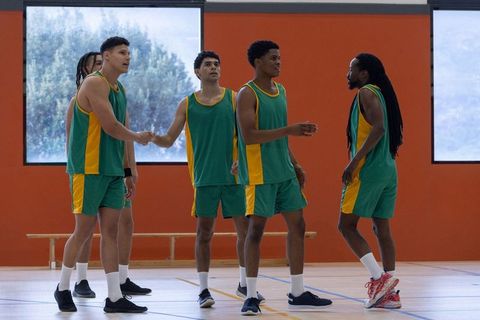 Diverse Male Basketball Team Displaying Sportsmanship on Indoor Court