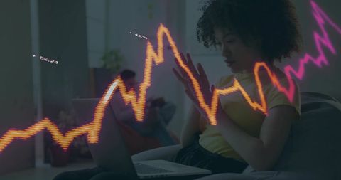 Woman working from home on laptop with neon financial chart overlay showing analytics