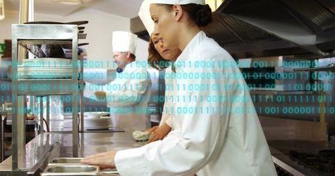 Female chef arranging pans at kitchen pass with binary overlay visualizing smart kitchen
