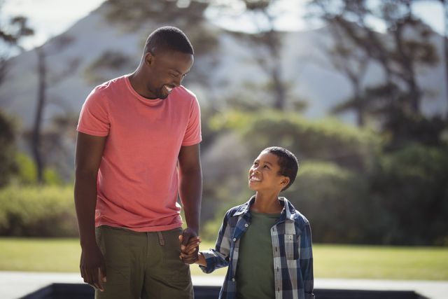 Father and son enjoying quality time together outdoors on a sunny day. Ideal for use in family-oriented advertisements, parenting articles, and promotional materials highlighting family bonds and outdoor activities.