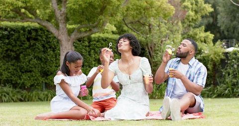 African American Family Enjoying Quality Time Blowing Bubbles Outdoors