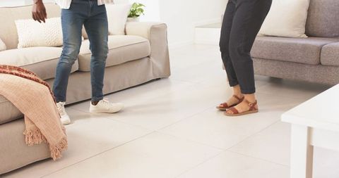 Couple standing in modern living room wearing jeans and sandals, neutral minimalist decor