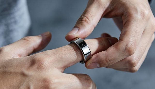 Placing silver ring with black inlay and triple mark on finger closeup