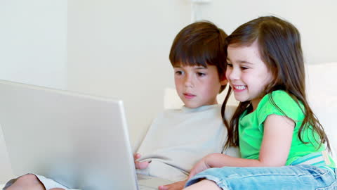 Smiling Siblings Enjoying Laptop Time Together