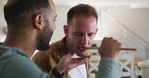 Same-Sex Couple Tasting Food at Home Together in Kitchen