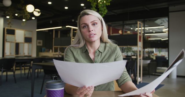 Focused woman holding documents in modern office space - Download Free Stock Images Pikwizard.com