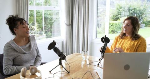 Recording relaxed conversation podcast with two women in bright home studio using laptop