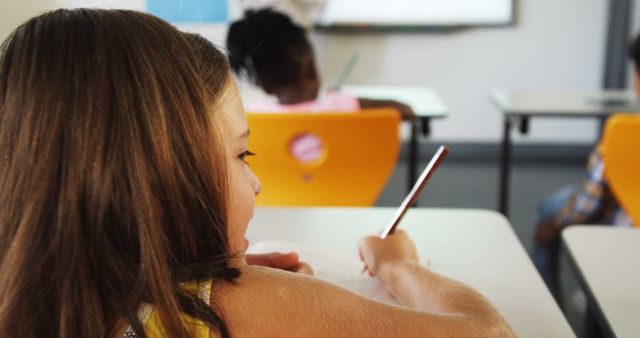 Focused Young Girl Writing in Classroom with Diverse Students - Download Free Stock Images Pikwizard.com